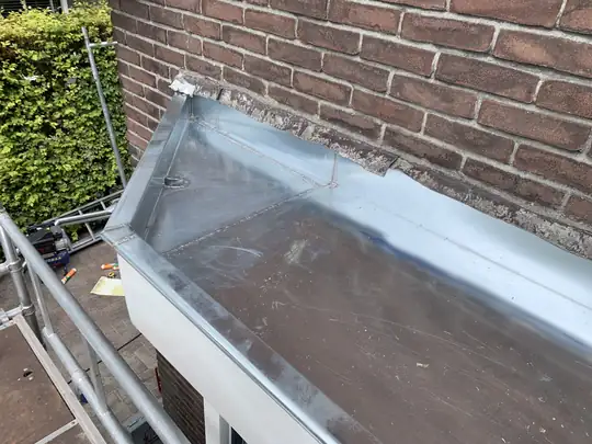 Zinken afwerking tegen een bakstenen muur
