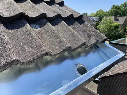 Zinken goot met regenwater op een schuin dak
